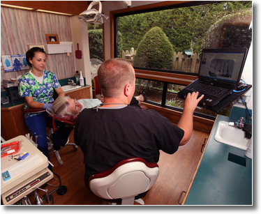 Dr. Wiles, a hygienist, and a patient review dental x-rays on a computer